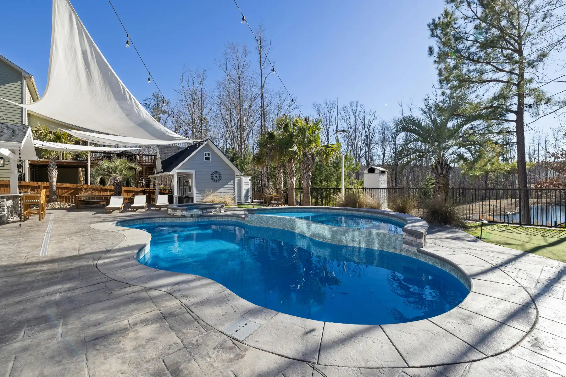 Stamped concrete pool deck in a stone pattern around a curved pool and spa